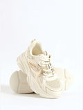 A pair of chunky platform sneakers in a warm cream or off-white color, featuring mesh panels, thick sculpted soles, and lace-up fronts, set against a seamless white background.